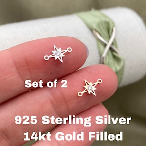 May include: Set of two star-shaped connector charms, one in sterling silver and one in 14kt gold filled. Each charm features a small clear rhinestone in the centre.
