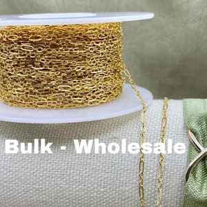 May include: A spool of gold-colored chain with an oval and round link design. The chain is displayed with the text "Bulk - Wholesale". The chain is on a white spool.
