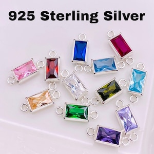 May include: A collection of rectangular 925 sterling silver charms with various colored rectangular gemstones. The gemstones include pink, red, blue, white, green, yellow, and purple. Each charm has a small loop on each end.