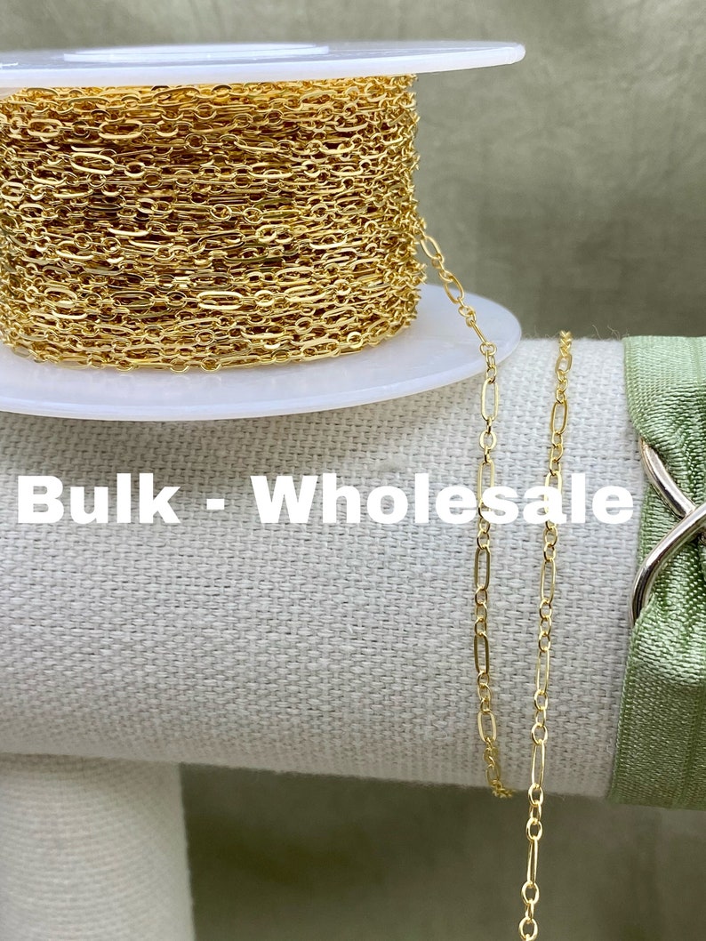 May include: A spool of gold-colored chain with an oval and round link design. The chain is displayed with the text "Bulk - Wholesale". The chain is on a white spool.