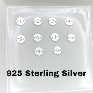May include: Ten silver-toned metal discs with numbers 1 through 9 and 0, each with two small holes, on a white surface. 925 Sterling Silver.