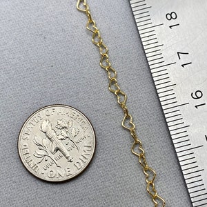 May include: A gold heart-shaped chain necklace, measured against a ruler. The chain is approximately 18 inches long.