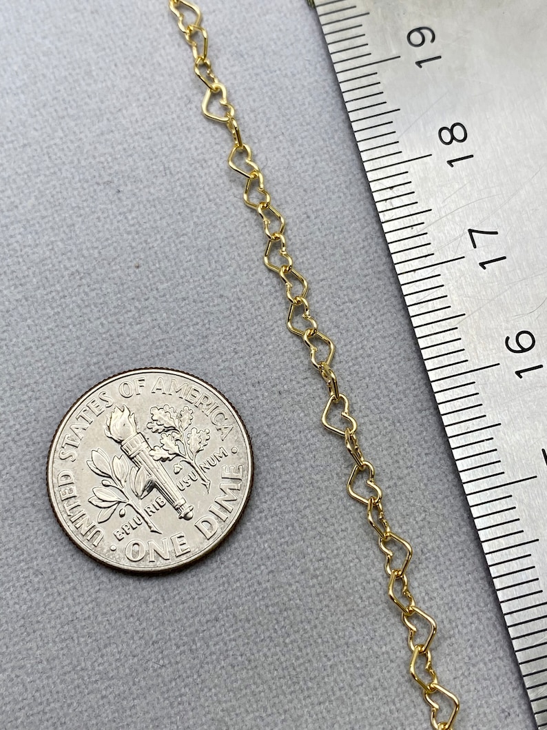 May include: A gold heart-shaped chain necklace, measured against a ruler. The chain is approximately 18 inches long.