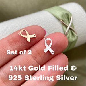 May include: Set of two ribbon charms, one gold filled and one sterling silver. The charms are in the shape of a ribbon with a loop at the top for attaching to jewelry.