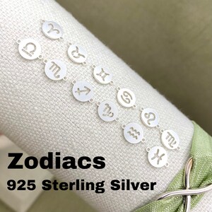 May include: A silver charm bracelet with 12 zodiac signs, including Aries, Taurus, Gemini, Cancer, Leo, Virgo, Libra, Scorpio, Sagittarius, Capricorn, Aquarius, and Pisces. The bracelet is made of 925 sterling silver and is labeled "Zodiacs 925 Sterling Silver".