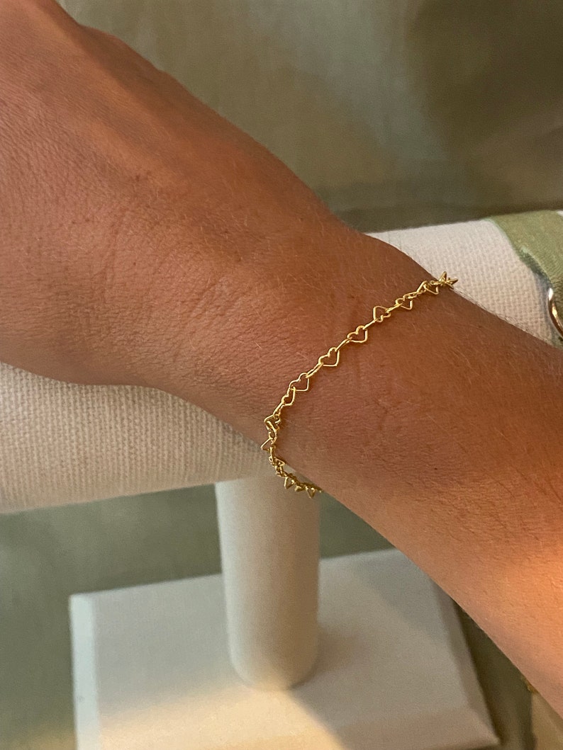 May include: A gold heart-shaped chain bracelet. The bracelet is delicate and dainty, and would make a great gift for a loved one.