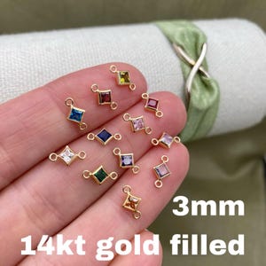 May include: Assortment of 14kt gold filled connectors with 3mm square-shaped gemstones in various colors. The connectors have two loops for attaching to jewelry.