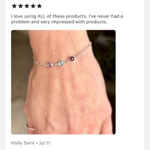 May include: A delicate silver bracelet featuring three colorful gemstones: a purple, a light blue, and a deep red. The bracelet is worn on a wrist. The text in the image says "I love using ALL of these products, I've never had a problem and very impressed with products."