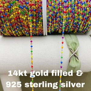 Puede incluir: Dos carretes de cadena de cuentas de colores, uno en oro de 14 quilates y otro en plata de ley 925. Las cuentas son pequeñas y coloridas, y la cadena es delicada.