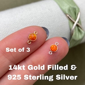 May include: Set of three 14kt gold filled and 925 sterling silver connector charms with orange opal stones.