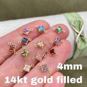 May include: Assortment of 14kt gold filled 4mm square connectors with different colored gemstones. Each connector has two loops for attaching jewelry.