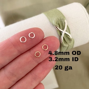 May include: Two silver jump rings and two gold jump rings, all in a hand. The rings are 4.8mm in outer diameter, 3.2mm in inner diameter, and 20 gauge.
