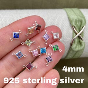 May include: Assortment of 4 mm square-shaped gemstone charms with silver double loop connectors. The charms are in various colors, including blue, green, purple, pink, red, and yellow. 925 sterling silver.