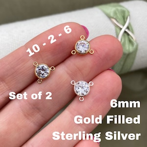 May include: Set of two 6mm clear cubic zirconia connector charms. One charm is gold filled and the other is sterling silver.