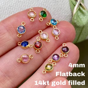 May include: A collection of 4mm flatback gemstone connectors in various colors, including blue, green, pink, and red, set in 14kt gold filled settings. The connectors have a small loop on each end.