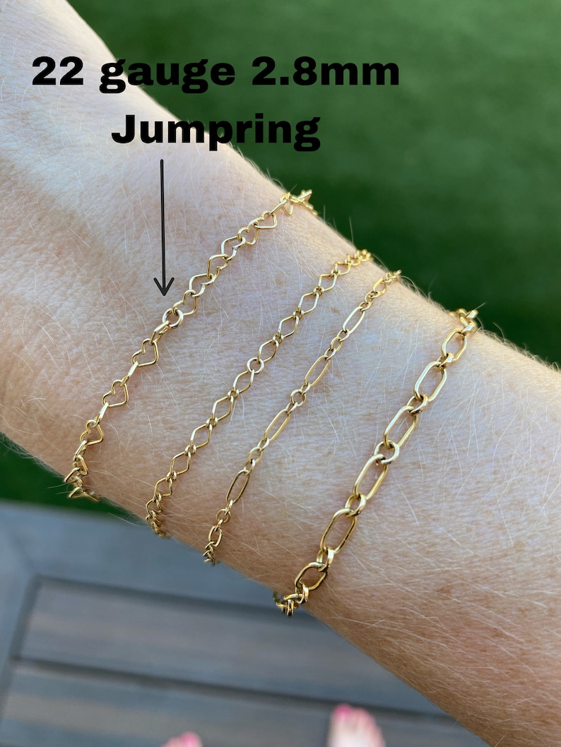 May include: Four gold chains of different styles and sizes on a person's wrist. The chains are 22 gauge and 2.8mm. The text "22 gauge 2.8mm Jump Ring" is visible above the chains.