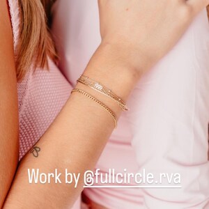 May include: Two women wearing pink shirts, one with a gold chain bracelet and another with a gold ring on her finger. The caption reads "Work by @fullcircle.rva".