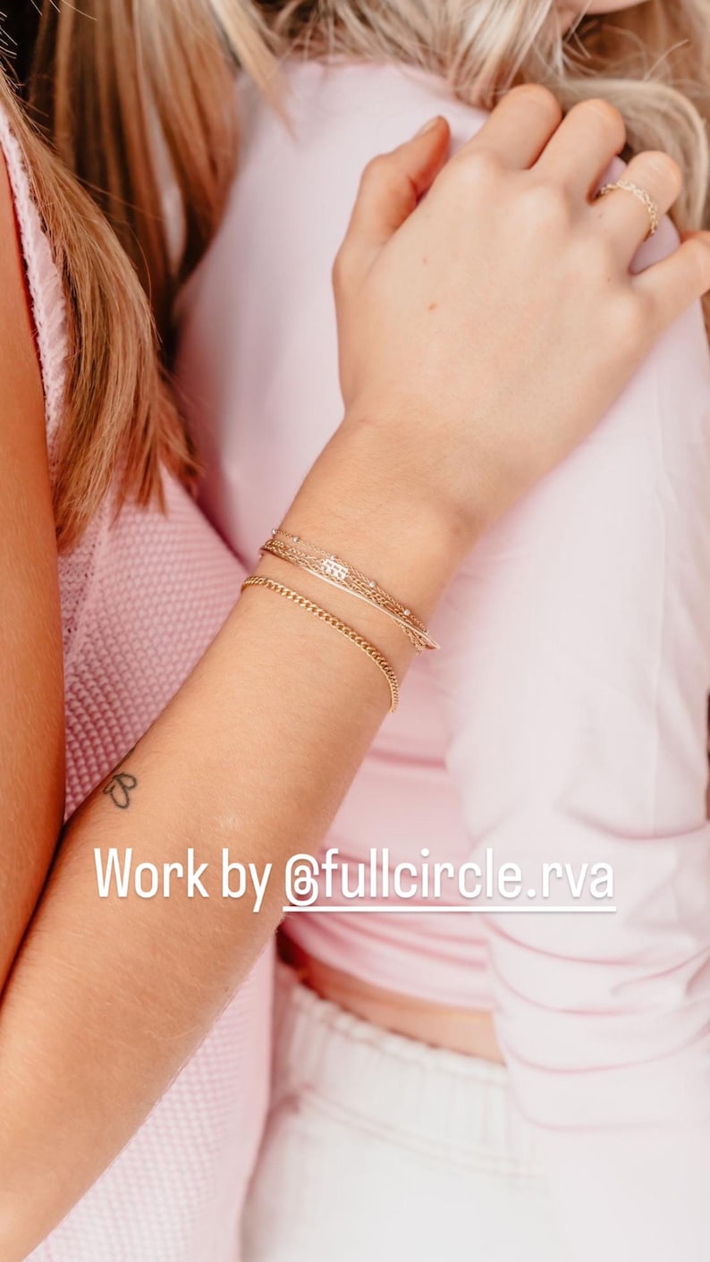 May include: Two women wearing pink shirts, one with a gold chain bracelet and another with a gold ring on her finger. The caption reads "Work by @fullcircle.rva".