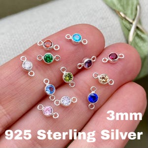 May include: A collection of 925 Sterling Silver connectors with colorful 3mm round gemstones. The gemstones are in various colors, including red, green, blue, purple, and clear. The text "3mm" and "925 Sterling Silver" are visible.