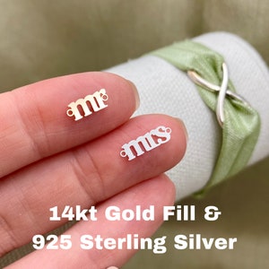 Puede incluir: Dos pequeños amuletos de metal, uno que dice "mr" y otro que dice "mrs". Los amuletos son de oro de 14 quilates y plata de ley 925.
