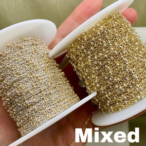 May include: Two spools of mixed-metal chain, one gold and one silver, are displayed. The chains are tightly wound on white spools. The word "Mixed" is printed in white block letters at the bottom of the image.