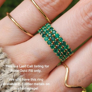 May include: A close-up of a hand wearing three gold rings with green gemstones. The text "This is a Last Call listing for Rose Gold Fill only. We still have this ring available in 5 other metals on our homepage!" is visible in the image.