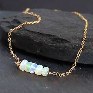 May include: A delicate gold chain necklace with a row of small, iridescent opal beads.