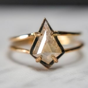 May include: A gold ring with a unique, faceted, kite-shaped diamond set in the center.