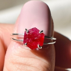 Könnte beinhalten: Ein silberner Ring mit einem roten Edelstein in sechseckiger Form.