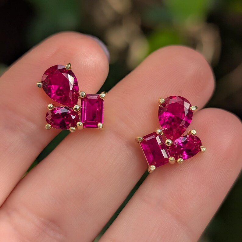 Peut inclure: Une paire de boucles d'oreilles dor&eacute;es avec des grappes de pierres pr&eacute;cieuses fuchsia vif. Chaque boucle d'oreille pr&eacute;sente un m&eacute;lange de tailles poire et rectangulaire, cr&eacute;ant un design unique. Les pierres sont serties dans du m&eacute;tal dor&eacute;.