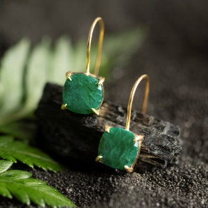 May include: A pair of gold earrings with green gemstone drops. The earrings have a simple design and are perfect for everyday wear.