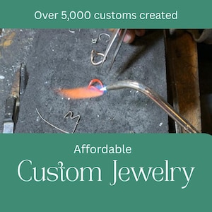 May include: A jeweller uses a torch to heat a piece of jewellery, with the text "Affordable Custom Jewelry" below. The image also includes the text "Over 5,000 customs created". The jewellery is being worked on a dark grey surface.