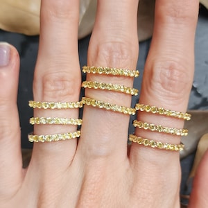 Puede incluir: Un conjunto de cinco alianzas de oro amarillo, cada una con una fila de pequeños diamantes amarillos.