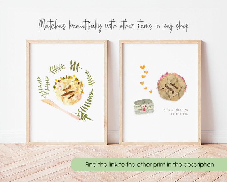 May include: Two framed prints with pressed flower art. The first print features a yellow and brown arepa with green leaves around it. The second print features a pink arepa with a yellow heart above it and the text "eres el dieblitos de mi arepe".