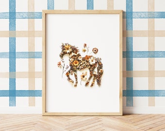 May include: A framed print of a horse made from dried flowers and leaves. The horse is brown and white and is surrounded by a white background. The frame is a light wood color.