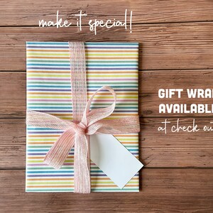May include: A colorful striped gift wrap with a pink ribbon and a blank gift tag. The text "GIFT WRAP AVAILABLE at check out" is visible in the image.