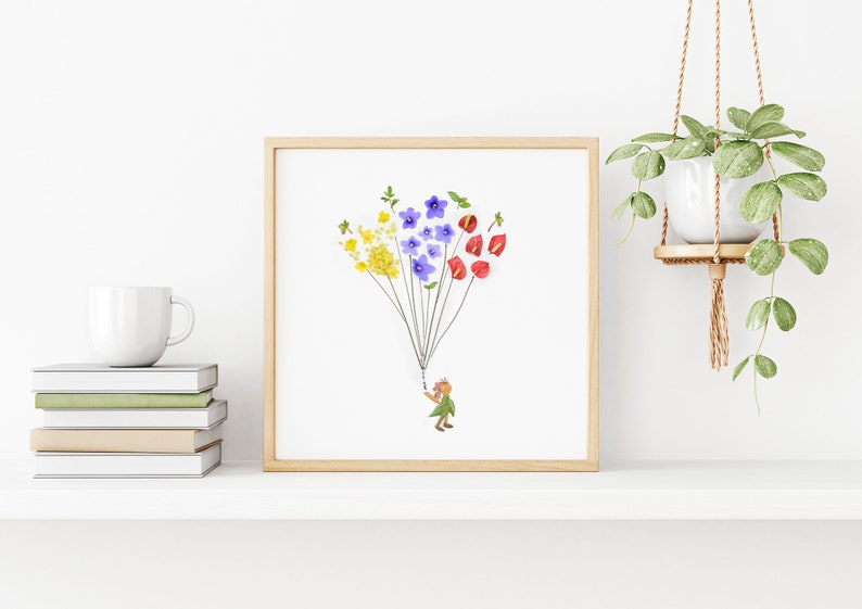 May include: A framed print of a whimsical illustration featuring a small figure holding a bunch of colorful pressed flowers, resembling a hot air balloon.