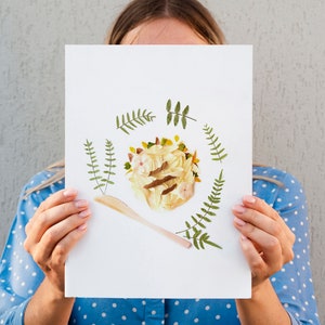 May include: A white card with a pressed flower arrangement in the center. The arrangement is a circle of yellow and white flowers with a brown stem and green leaves. A wooden spoon is placed below the flower arrangement. The card is surrounded by a border of green leaves.