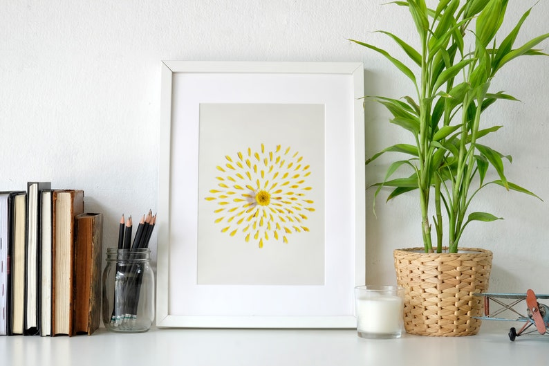 daisy art in a white frame leaning on office desk