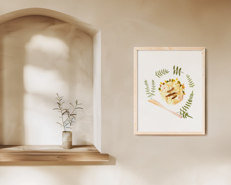 May include: A framed print of a pressed flower arrangement in a circle with a wooden spoon in the bottom right corner. The flowers are yellow, white, and brown, and the leaves are green.