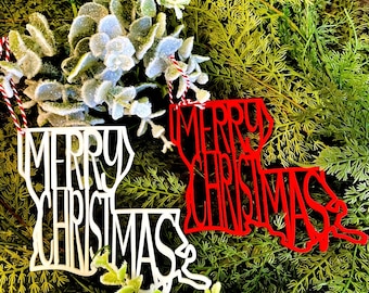 May include: Two Christmas ornaments shaped like the state of Louisiana. One is red with the words "Merry Christmas" and the other is white with the words "Merry Christmas".