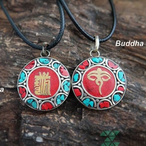 May include: Two round pendant necklaces with black cords. One pendant features a red center with gold lettering and the word "Kalachakra". The other pendant has a red center with a gold eye design and the words "Buddha Eyes". Both pendants have turquoise and red accents.