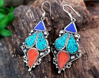 May include: A pair of silver earrings with turquoise and lapis lazuli stones. The earrings are in the shape of a teardrop with a small triangle at the top. The earrings are intricate and detailed.
