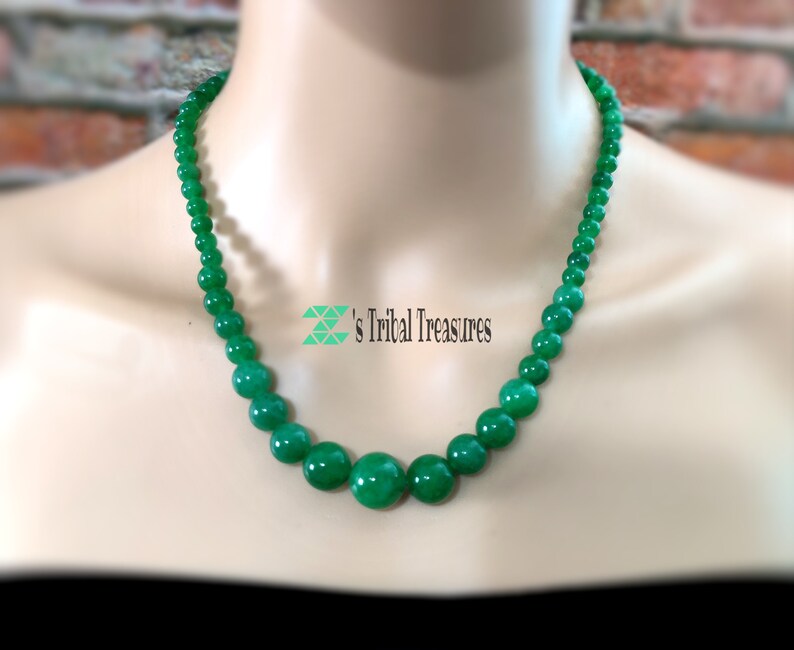 May include: A green jade bead necklace with a rounded shape. The necklace is on a white mannequin.