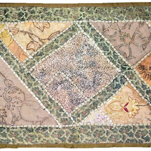 May include: A patchwork throw pillow with a diamond-shaped design in the center. The pillow is made of various fabrics in shades of beige, brown, and green. The fabric is decorated with sequins and embroidery.