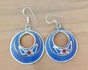 May include: A pair of silver hoop earrings with blue enamel and red accents. The earrings have a delicate, intricate design.