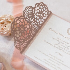 May include: A pink and white wedding invitation with a delicate lace design. The invitation features the names "Emma James and" and the date "29th August 2025".