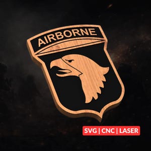 May include: A wooden shield-shaped emblem featuring the text AIRBORNE at the top and a stylized eagle head in the center. The design has a natural wood grain finish with black recessed areas. A red rectangular label displays the text SVG | CNC | LASER.