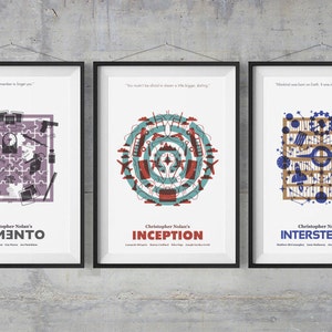 May include: Three framed movie posters for Christopher Nolan films: Memento, Inception, and Interstellar. Each poster features a unique, stylized graphic design with quotes and film titles. The posters are in black frames, hanging against a gray concrete wall.