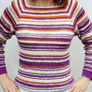 Pu&ograve; includere: Un maglione in maglia a maniche lunghe con un motivo a righe orizzontali nei toni del viola, arancione brillante e bianco sporco. Il capo presenta uno scollo quadrato e polsini a coste all'estremit&agrave; di ogni manica, in filato testurizzato.